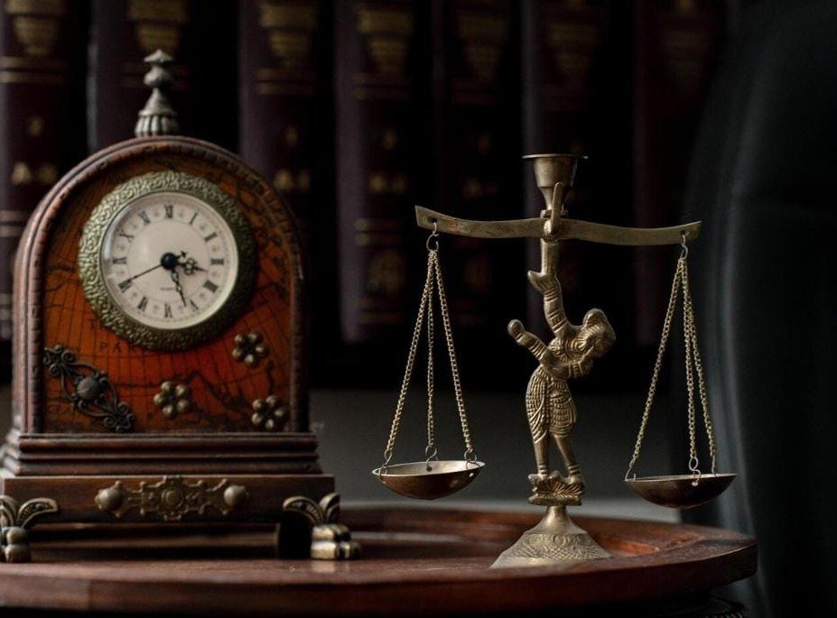 Antique clock beside a statue of the scales of justice